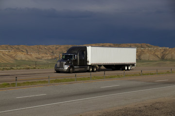 A silver or grey Western Star Semi-Tractor pulls a White unmarked trailer along Interstate 80 in Rural Wyoming on May 4th, 2017.