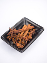 Star anise and cinnamon in a bowl isolated on white background