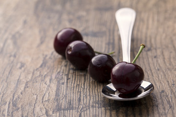 Close-up of cherries in a silver spoon on brown background