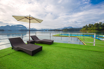 Lake view in summer with relaxation seat and umbrella in wooden terrace at Thailand Summer Season