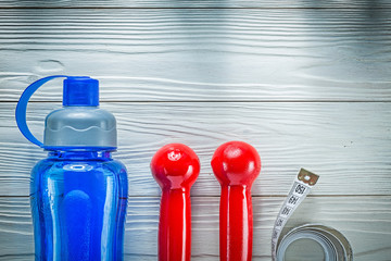 Measuring tape plastic shaker red dumbbells on wooden board fitn