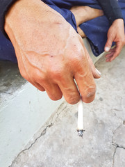 asian man's hand holding burning traditional cigarette in hand