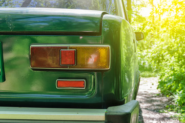 Detail of a rusty green car abandoned by the side of the road