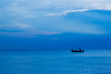 beautiful sunrise over the sea and silhouette fishing boat with cloudy sky in Thailand. Blue filter photo.