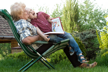 Grandmother and grandson reading a book outdoors.Funny stories.