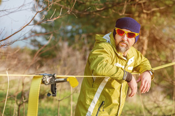 Close-up portrait of a man adjusting slacklining equipment before performing crazy slacklining tricks and walking on slacklin in a park in nature