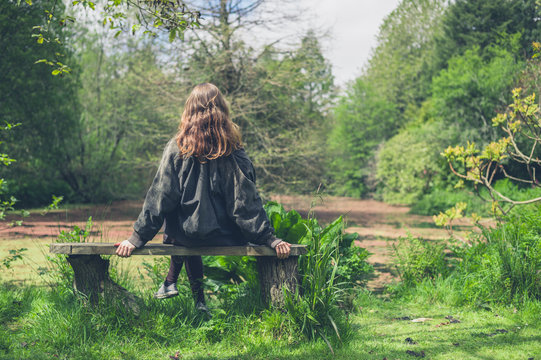 Woman sitting on bench by pond