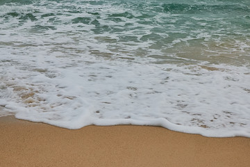 Soft wave of blue ocean on sandy beach. Background.