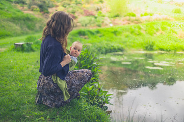 Young woman with baby by pond