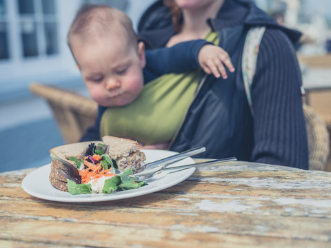 Mother with baby eating sandwich