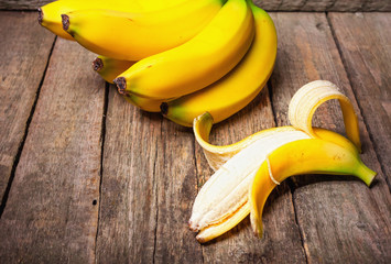 Bundle of bananas and a sliced banana on vintage wooden background, selective focus