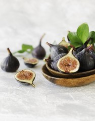 dark blue Fresh figs in a wooden bowl on a white marble table, selective focus