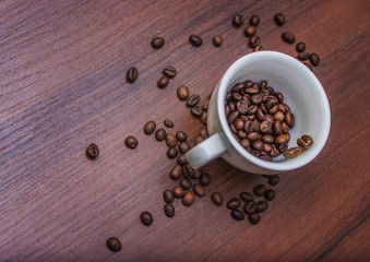 Cup with coffee beans on a brown tree