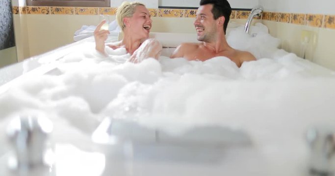 Young Couple In Bath Together Drink Champagne Talking, Man And Woman Lover Enjoy Spa At Home Slow Motion 60