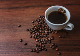 Cup with coffee on a tree with coffee beans