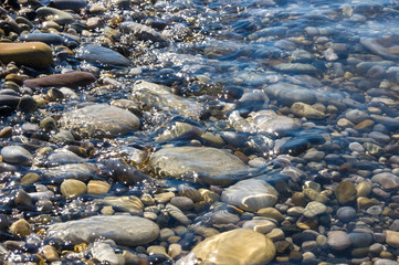 sea pebble beach with multicoloured stones, waves with foam