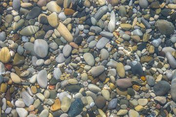 sea pebble beach with multicoloured stones, waves with foam