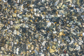 sea pebble beach with multicoloured stones, waves with foam