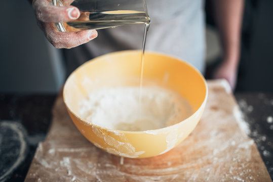 Male baker hands adds ingredients to the bowl