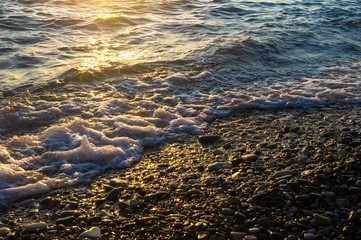 sea pebble beach with multicoloured stones, waves with foam