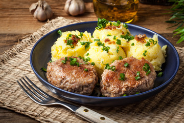 Meatballs served with boiled potatoes on a plate.