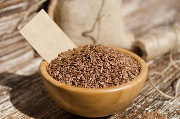 Close up of brown flax seeds  in wooden bowl on a rustic table. Superfood: linseeds are high in omega-3 fatty acids, essential for good health. Healthy eating ,vegan diet concept.