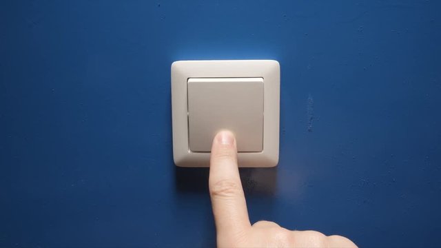 Human hand turn off a power button on a blue wall