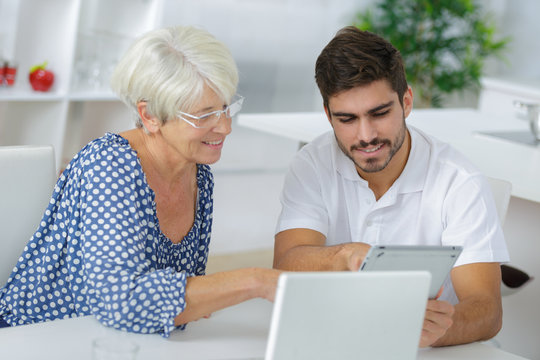 Young man and elderly lady looking at tablet screen