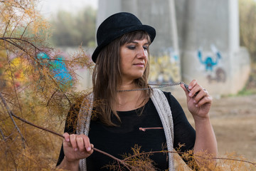 Mujer joven con sombrero junto al puente de cemento