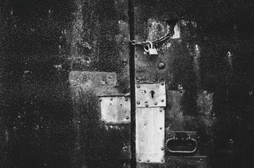 Grunge rusty old aged metal door with locker closeup. Black and white postcard. Empty moody background poster template.