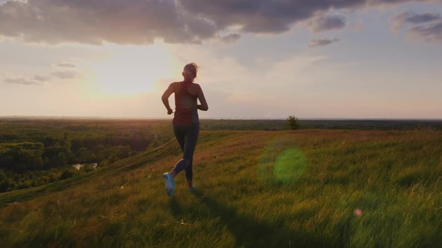 Young woman jogging in a scenic spot at sunset. Back view. 4K slow motion video