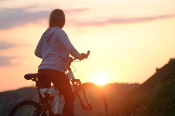 Obraz na płótnie Canvas girl riding bike in sunset