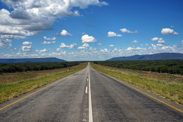 Endlose Asphaltstraße durch die Wüstenlandschaft Namibias