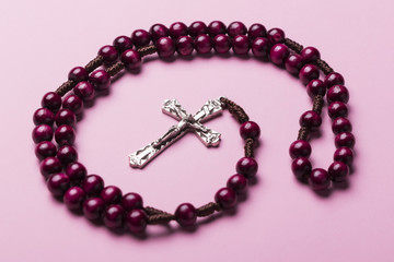 Rosary on a pink background. Christian cross.