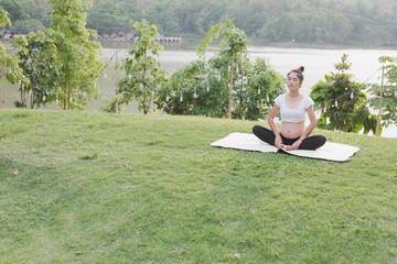 asian pregnant woman practicing yoga on green grass in public park.  concept of prenatal exercise, maternity, fitness, healthy lifestyle and relaxation.