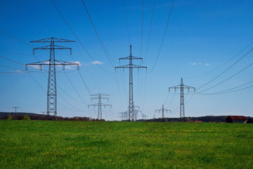 Mehrere Strommasten zur Energieliefeung auf der grünen Wiese