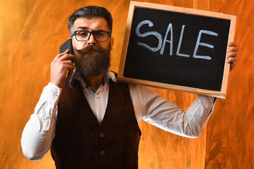 Bearded man, brutal caucasian hipster with smartphone holding sale inscription