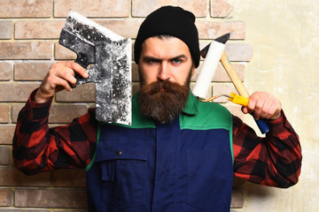 bearded builder man holding various building tools with serious face