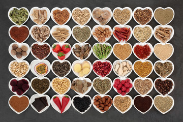 Aphrodisiac food sampler of foods to promote sexual health in heart shaped china bowls on slate background.
