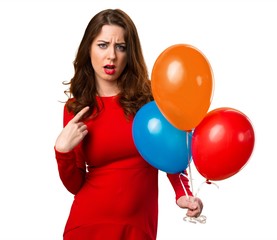 Beautiful young girl holding balloons and making surprise gesture