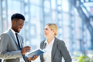 Portrait of two young business colleagues, one of them African,  discussing work smiling cheerfully...