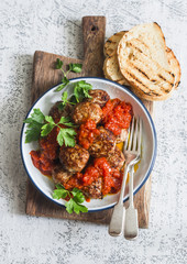 Baked meatballs with tomato sauce and herbs on a wooden cutting Board on white background. Top view. Delicious lunch