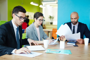 Group of busy managers working with papers in office