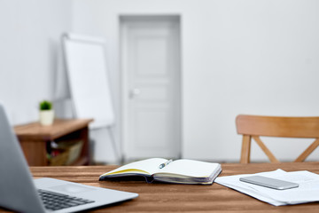 Workplace of modern manager with open notebook, laptop, smartphone and papers