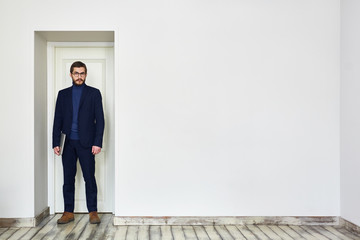 Businessman in formalwear standing by white door