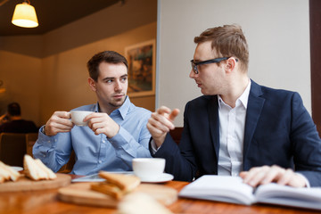 Portrait of two business people talking during casual meeting at lunch in cafe