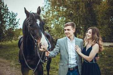 Couple in love walking in the woods with a horse.