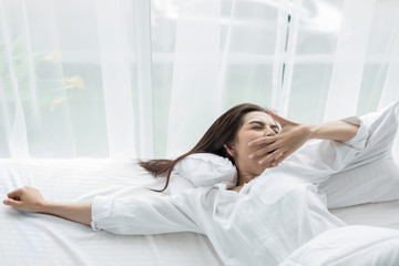 Asian woman Beautiful young smiling woman sitting on bed and stretching in the morning at bedroom after waking up in her bed fully rested