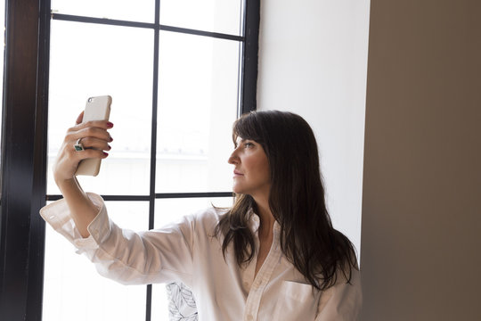 Beautiful business woman taking a selfie by the window