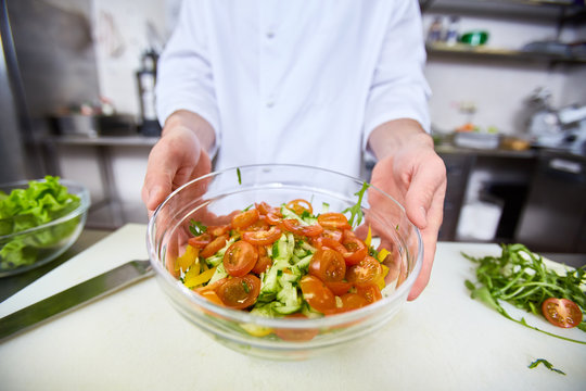 Chef showing cooked salad in bowl